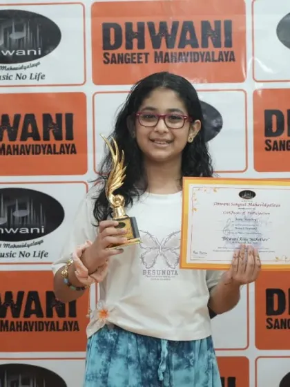 A young student proudly holds her certificate and trophy.
