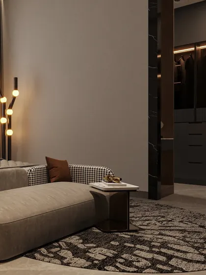A view of the seating area at the foot of the bed, with a glimpse into the adjoining walk-in closet. The houndstooth pattern on the sofa adds a classic touch.