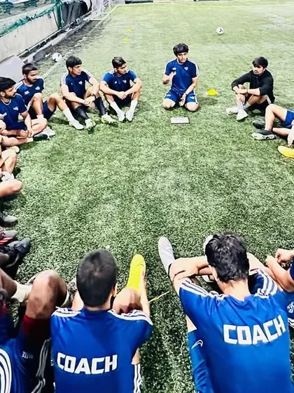 A team of coaches sits in a circle for a debrief. Continuous learning and sharing knowledge among ourselves is key to providing the best training for our kids.