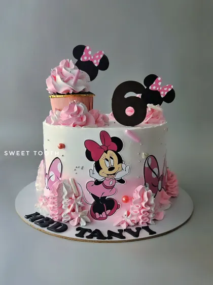 A Minnie Mouse cake with a matching cupcake on top. This chocolate mousse cake for Tanvi's 6th birthday is a fun and pretty take on a classic character.