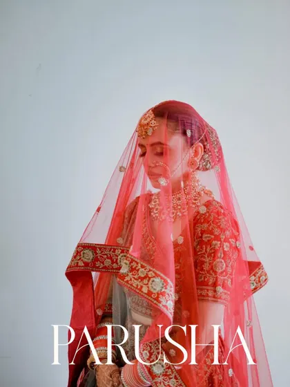 An elegant, simple portrait of the bride under her red veil. The clean background and soft light put all the focus on her.