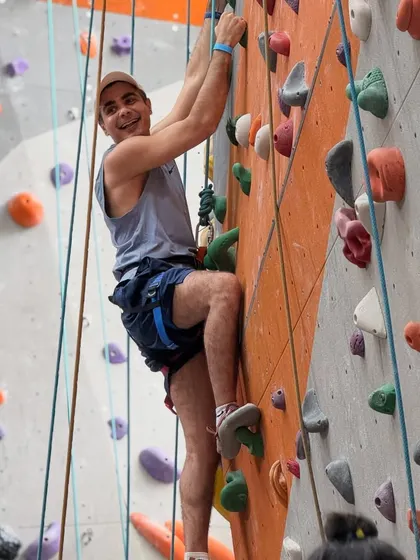 A smiling climber pauses on his way up the wall. The sense of accomplishment and fun is what keeps our community coming back for more.