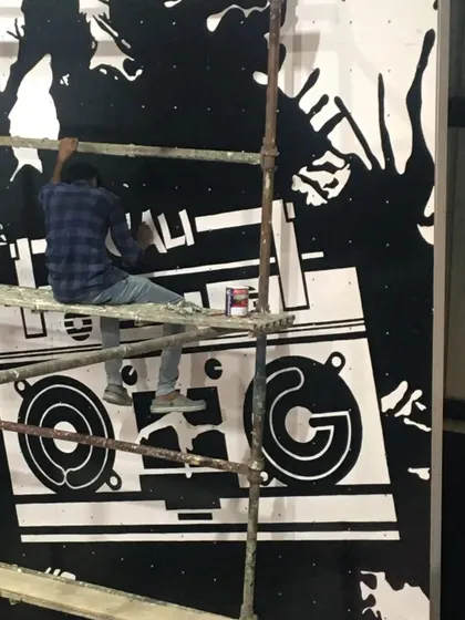 One of our artists on scaffolding, hand-painting the fine details of a large boombox mural for a gym. Even for large graphic pieces, we ensure every line is sharp and clean.