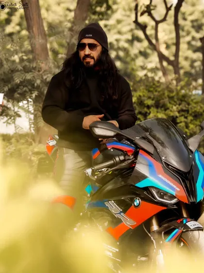 A more relaxed portrait, with the rider leaning against his bike. The natural, wooded background provides a great contrast to the modern machine.