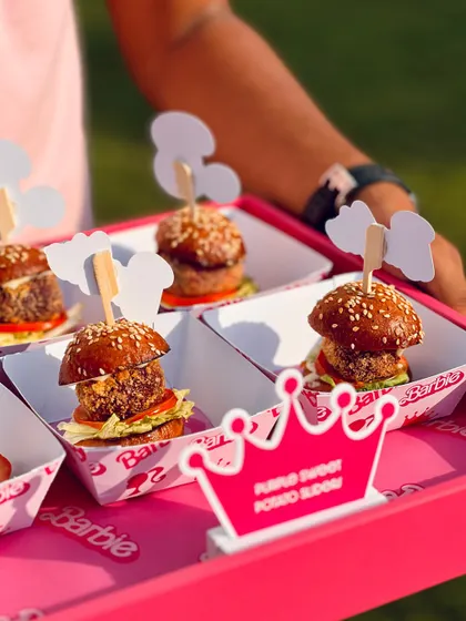 A close-up of the purple sweet potato sliders, each with a custom Barbie silhouette topper, served on a bright pink tray.