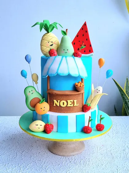 A full view of the fruit-themed cake on its stand.