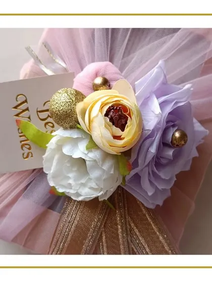 The beautiful packaging for a wedding gift, wrapped in tulle with a floral arrangement and a 'Best Wishes' card.
