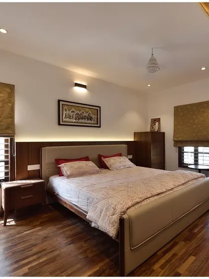 A serene master bedroom design with hardwood flooring, custom wood paneling behind the bed, and layered lighting to create a warm and restful retreat.