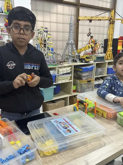 Two young boys are deeply engaged in a building session, sorting through pieces to find the perfect one for their creation.