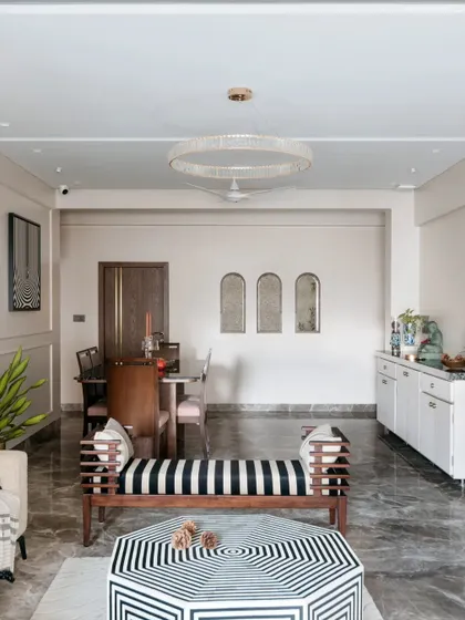A wide view of this living and dining area shows how different zones can coexist harmoniously. The striped bench, geometric coffee table, and elegant dining set are all tied together by a consistent color palette and a focus on clean lines.