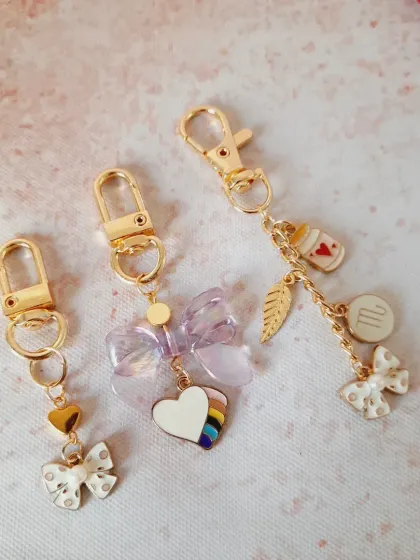 A collection of custom bag charms, showing the different ways you can combine bows, hearts, initials, and other charms to create your own unique accessory.
