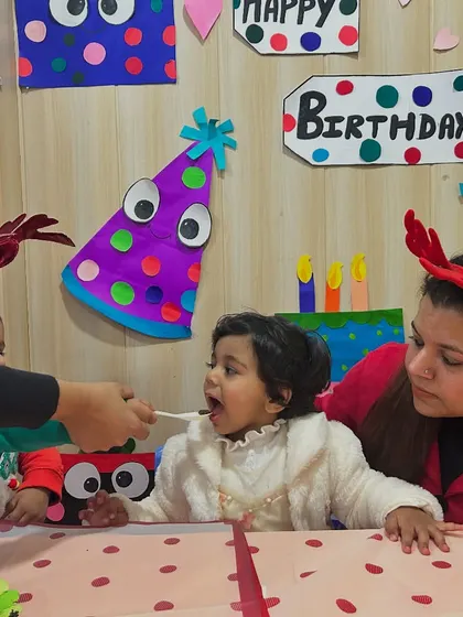 An instructor feeds the birthday girl a piece of cake as her mother looks on, a sweet tradition in our classes.