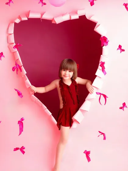 Peeking through a heart! This playful shot captures a young girl's fun-loving spirit during her Valentine's Day mini-session, using a creative paper-torn heart prop.