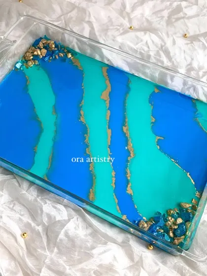 A beautiful and functional serving tray with a blue, teal, and gold abstract design. The geode crystal corners add a touch of luxury.