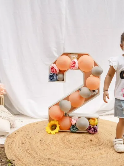 A happy toddler girl stands next to her birthday prop during her outdoor session.