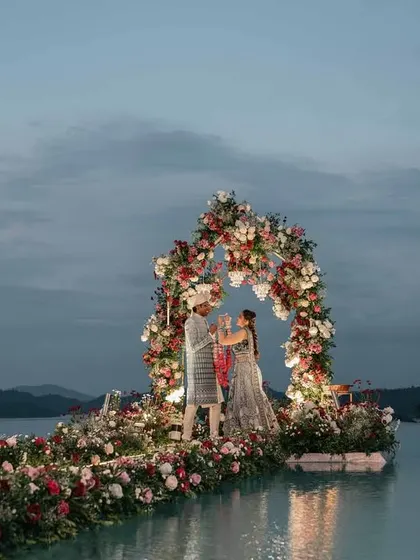 Another shot of the stunning infinity pool Varmala ceremony. The twilight sky and the reflection of the floral arch on the water create a scene of unparalleled beauty.