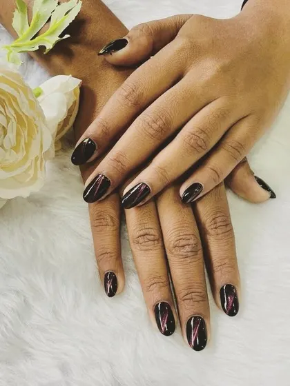 A dark and moody design with a twist. These nails feature a deep, almost-black base with subtle streaks of metallic red for a unique and edgy effect.