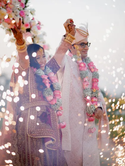 A grand celebration moment for Hitesh and Aarishma, surrounded by sparklers as they raise their hands in joy after the Varmala ceremony.