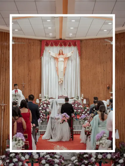 A wide shot of a Christian wedding ceremony, capturing the couple at the altar under the serene gaze of a statue of Jesus.