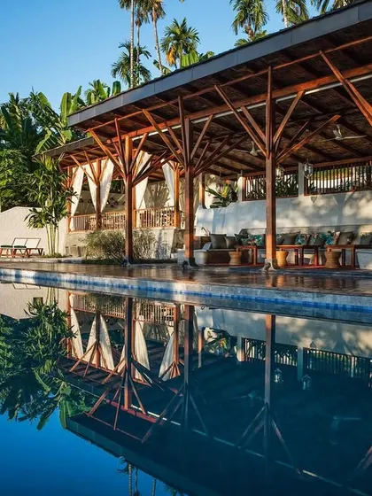 The reflection of the timber-framed restaurant pavilion in the calm waters of the infinity pool.
