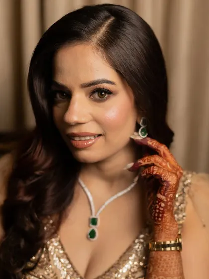 A close-up portrait of Ashima, highlighting her flawless skin and the elegant emerald necklace.