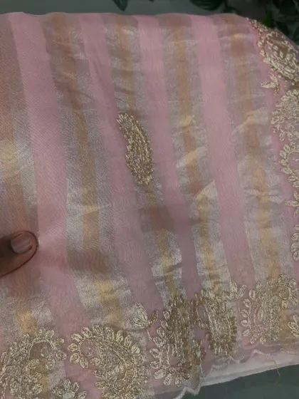 A lovely pastel pink tissue stripes organza saree with a paisley motif and gold embroidery on the border.