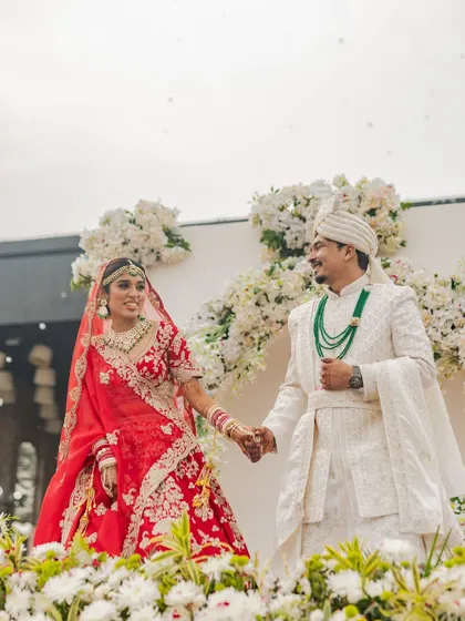 A classic portrait of the newly married couple. Rahul and Riya stand hand-in-hand, surrounded by beautiful white flowers, a timeless shot that will be cherished for a lifetime.