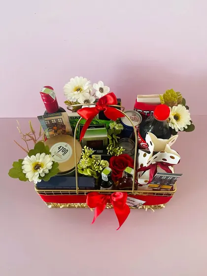 This metal basket hamper is curated for a celebration, featuring wine, snacks, and other party essentials. Please note, alcohol delivery is subject to local regulations.