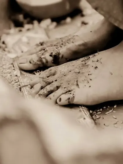 A detail shot from a Haldi ceremony, focusing on the tradition and the earthiness of the ritual. This artistic, sepia-toned photo captures the texture and moment beautifully.