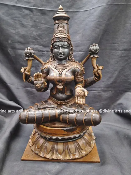 A full view of a seated Mahalakshmi wax model on a lotus base. The Abhaya and Varad mudras of her lower hands are clearly defined, promising blessings and protection to her devotees.