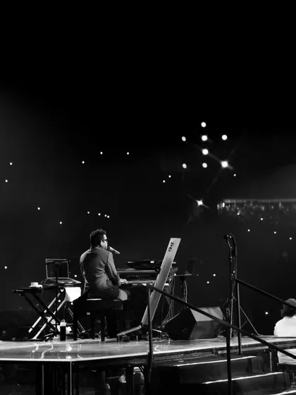 A solitary moment for the maestro, A.R. Rahman, at his keyboard against a backdrop of stars from the audience's phones. This image captures the profound connection between the artist and the crowd.
