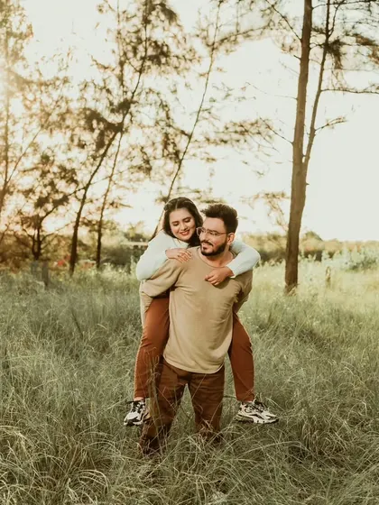 A fun piggyback ride in a grassy field, capturing a moment of pure, unscripted joy. We believe these playful moments are an essential part of any love story.