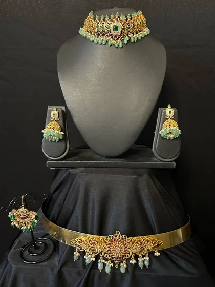 This rental set includes a beautiful kemp stone choker, matching jhumkas, a maang tikka, and a simple vaddanam. It's a great combo for a bridesmaid or for a smaller function.