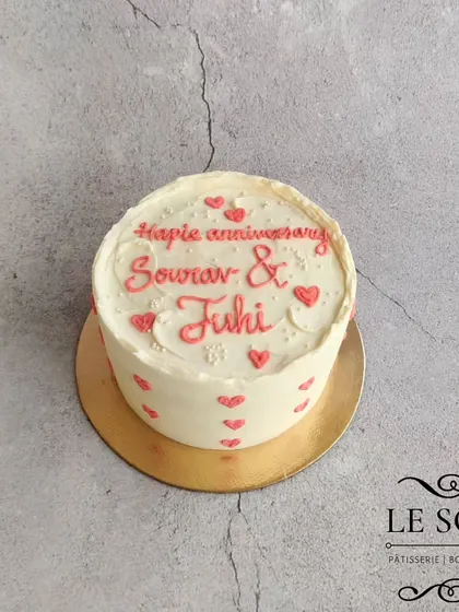 A simple and sweet anniversary cake. This half-kg Vanilla Chocolate cake is decorated with minimalist pink hearts and delicate piping, proving that a simple design can still be full of love.