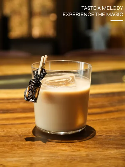 A playful cocktail garnished with a Melody toffee, evoking childhood nostalgia.