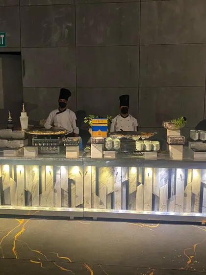 A full view of a live station spread at a modern event. This setup features multiple chefs preparing different dishes on the spot, showcasing our ability to manage diverse live counters simultaneously.