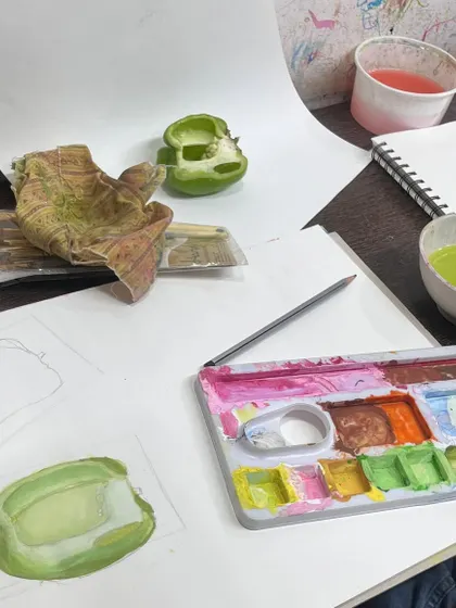 The artist's desk during a still life session. You can see the reference object, initial sketches, and the color palette used to bring the vegetable study to life on paper.