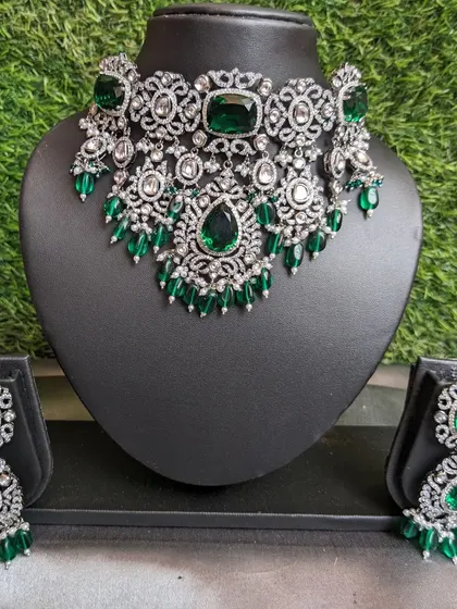 This Victorian-style choker is a current trend and a personal favorite. It features American Diamond and emerald stones with beautiful emerald-colored strawberry beads, perfect for making a statement at your reception.