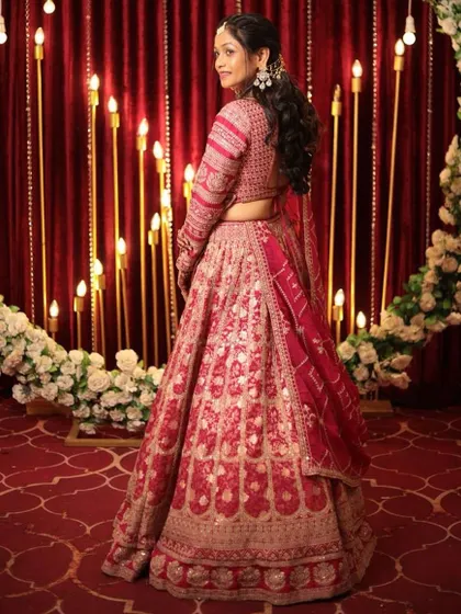 A back view of the pink bandhani-style lehenga, showing the elegant hairstyle and back details of the blouse.