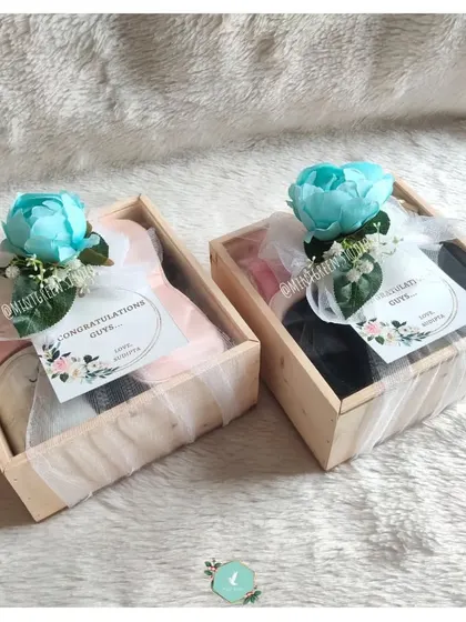 Two congratulations hampers packed in rustic wooden pinewood boxes. The blue flower adds a pop of color and a touch of elegance to the wrapping.