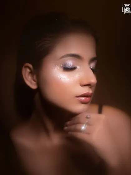 This shot, with its warm, earthy tones, gives the glitter makeup a soft and glamorous feel. The focus is on the flawless skin and the gentle shimmer on the eyelids.