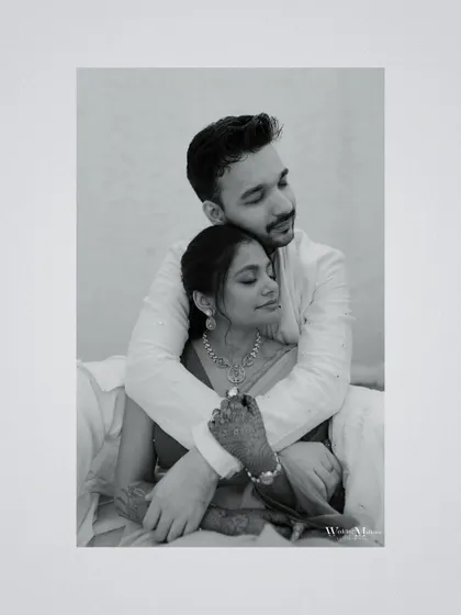 A tender black and white portrait of the groom embracing the bride from behind. This intimate shot focuses on their connection and the quiet moments of love.