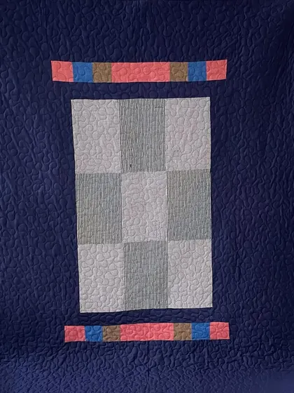 The reverse side of the checked shirt memory quilt, featuring a solid navy blue that highlights the quilting.
