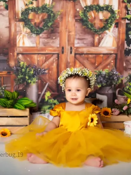 This little princess is surrounded by sunflowers, wearing a gorgeous yellow dress that lights up the room.