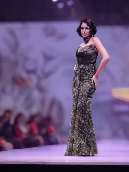 A profile shot on the runway to emphasize the sleek, form-fitting design of this glittering gown. The side angle highlights the model's posture and the intricate texture of the fabric.
