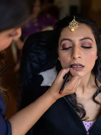 A close-up of the makeup artist applying lipstick, a classic getting-ready shot.