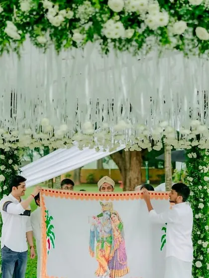 A sacred moment before the vows. The Antarpat ceremony, framed by a minimal mandap of white florals and fresh greenery, creates a sense of serene anticipation.