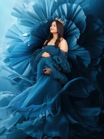 A fantasy portrait where a woman's blue gown seems to merge with a giant blue flower behind her. This creative edit results in a unique and visually striking image.