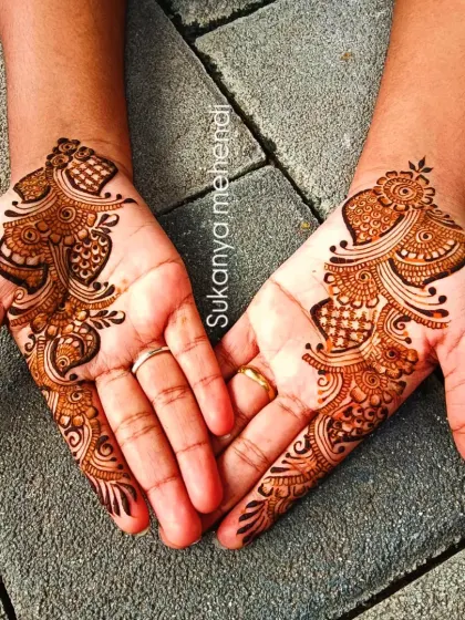 A classic Arabic henna design. The pattern flows diagonally across the back of the hands, featuring paisley motifs and intricate fillers for a very graceful look.