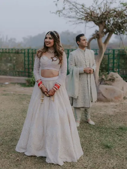 A beautiful portrait of the couple in an outdoor setting, with the bride in the foreground and the groom slightly behind, creating a sense of depth.
